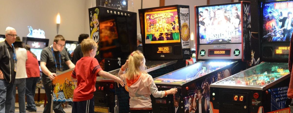 Two children playing pinball at the Pinball Expo.